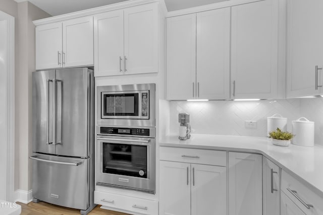 109 Crested Coral Dr, Holly Springs, NC 27540 - kitchen with appliances with stainless steel finishes, light countertops, white cabinets, backsplash, and light wood finished floors
