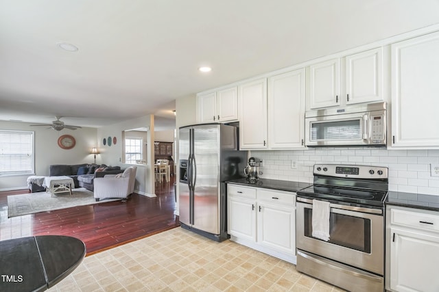 6 Newgate Ct, Durham, NC 27713 - kitchen with appliances with stainless steel finishes, open floor plan, white cabinetry, dark countertops, and tasteful backsplash