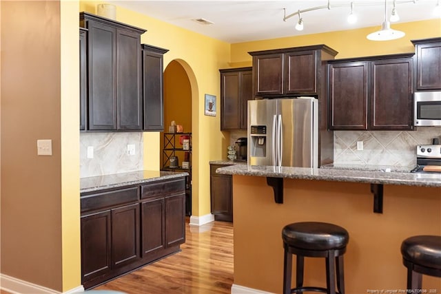 101 Birdsong Ct, Aberdeen, NC 28315 - kitchen featuring stainless steel appliances, a breakfast bar area, arched walkways, dark stone countertops, and light wood-style floors