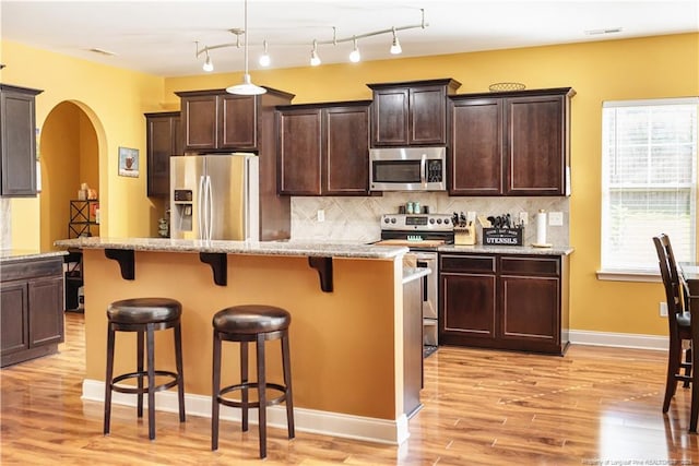 101 Birdsong Ct, Aberdeen, NC 28315 - kitchen with appliances with stainless steel finishes, a breakfast bar area, arched walkways, and light wood-type flooring