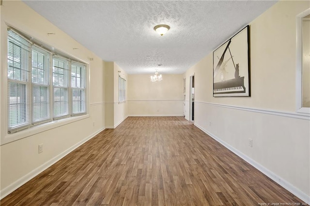 2547 Red Springs Rd, Raeford, NC 28376 - empty room with a chandelier, a textured ceiling, wood finished floors, and baseboards