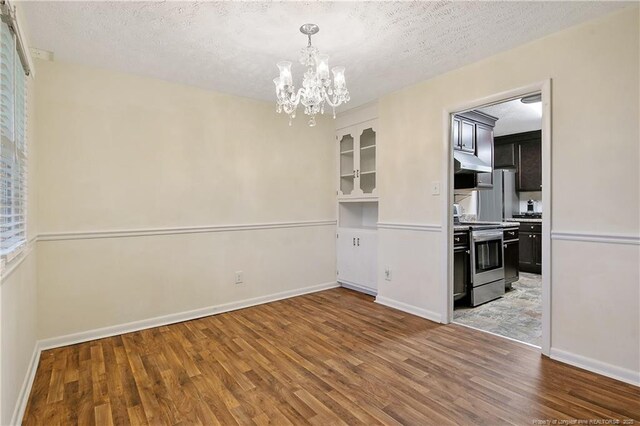 2547 Red Springs Rd, Raeford, NC 28376 - unfurnished dining area with wood finished floors, a chandelier, a textured ceiling, and baseboards