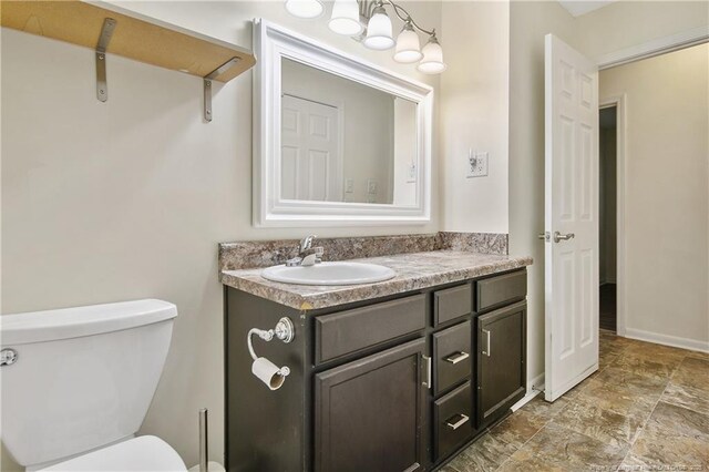 2547 Red Springs Rd, Raeford, NC 28376 - half bath featuring vanity, toilet, stone finish floors, and baseboards