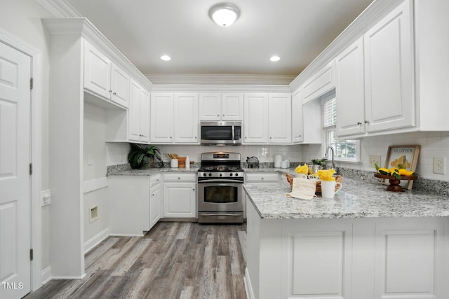 3020 Woods Walk Way, Rocky Mount, NC 27804 - kitchen featuring appliances with stainless steel finishes, white cabinets, wood finished floors, a peninsula, and decorative backsplash