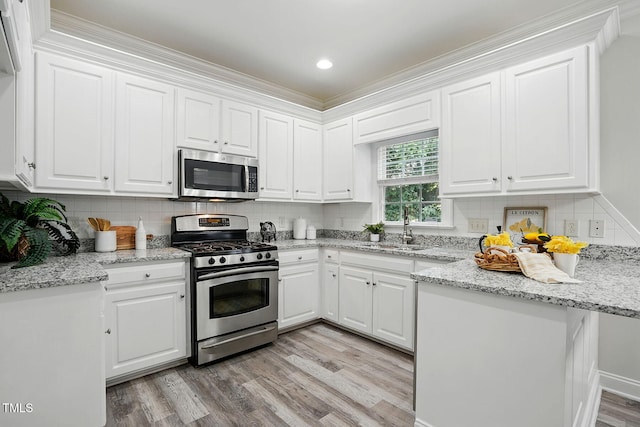 3020 Woods Walk Way, Rocky Mount, NC 27804 - kitchen with appliances with stainless steel finishes, a sink, light wood finished floors, white cabinetry, and ornamental molding