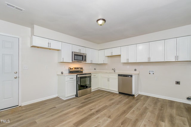 1110 Allgood St, Durham, NC 27704 - kitchen with stainless steel appliances, baseboards, light wood-style floors, and white cabinets