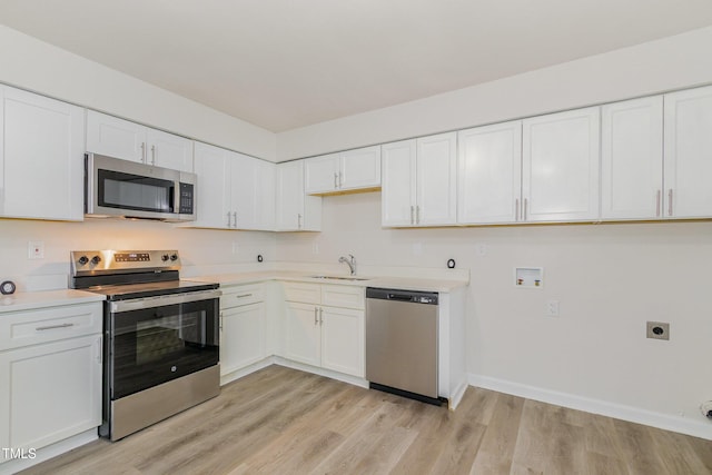 1110 Allgood St, Durham, NC 27704 - kitchen with stainless steel appliances, a sink, light countertops, light wood finished floors, and white cabinetry