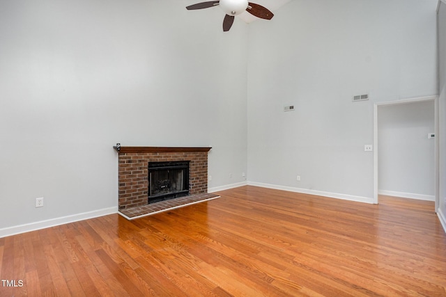 3306 Woodland Park Rd, Durham, NC 27703 - unfurnished living room featuring a high ceiling, ceiling fan, light wood-type flooring, a brick fireplace, and baseboards