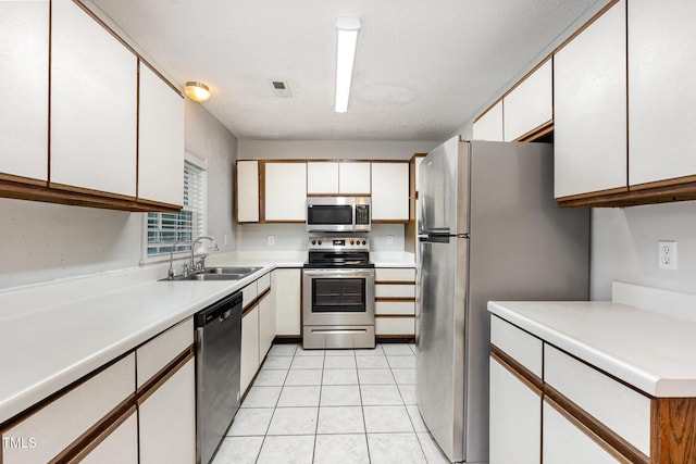 3306 Woodland Park Rd, Durham, NC 27703 - kitchen with appliances with stainless steel finishes, a sink, white cabinetry, and light countertops