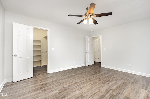 3306 Woodland Park Rd, Durham, NC 27703 - unfurnished bedroom with wood finished floors, a walk in closet, and baseboards