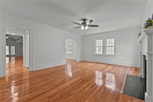 123 Ellington St, Fayetteville, NC 28305 - unfurnished living room with a ceiling fan, a fireplace with flush hearth, arched walkways, light wood-style floors, and baseboards