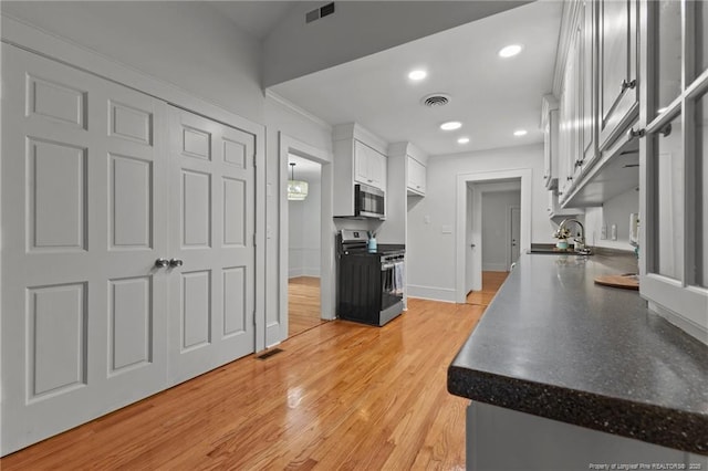 123 Ellington St, Fayetteville, NC 28305 - kitchen featuring appliances with stainless steel finishes, white cabinetry, dark countertops, baseboards, and light wood-style floors