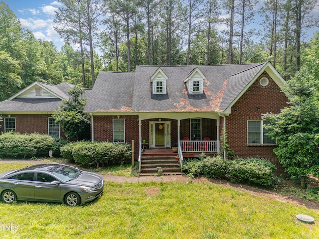 3304 Black Stallion Ct, Zebulon, NC 27597 - new england style home featuring a porch, brick siding, a front lawn, and roof with shingles