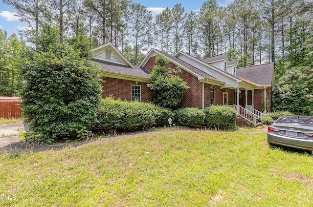 3304 Black Stallion Ct, Zebulon, NC 27597 - view of front of property with brick siding, a front yard, covered porch, and roof with shingles