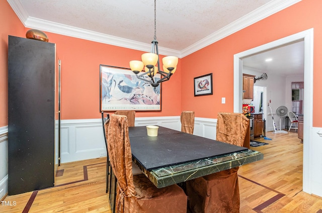 3304 Black Stallion Ct, Zebulon, NC 27597 - dining room featuring crown molding, a chandelier, light wood-type flooring, wainscoting, and a textured ceiling