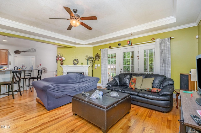 3304 Black Stallion Ct, Zebulon, NC 27597 - living room featuring a tray ceiling, light wood-style floors, a ceiling fan, ornamental molding, and french doors