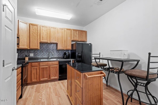 300 Gilman Ln Unit 101, Raleigh, NC 27610 - kitchen featuring black appliances, a sink, light wood-style floors, dark countertops, and tasteful backsplash