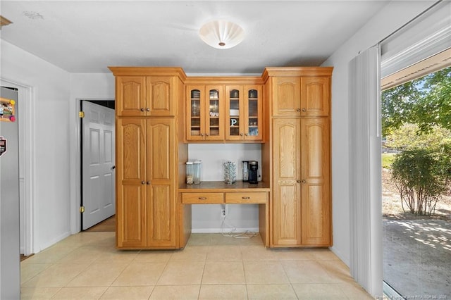 1926 Martindale Dr, Fayetteville, NC 28304 - kitchen featuring glass insert cabinets, light tile patterned flooring, baseboards, and brown cabinetry