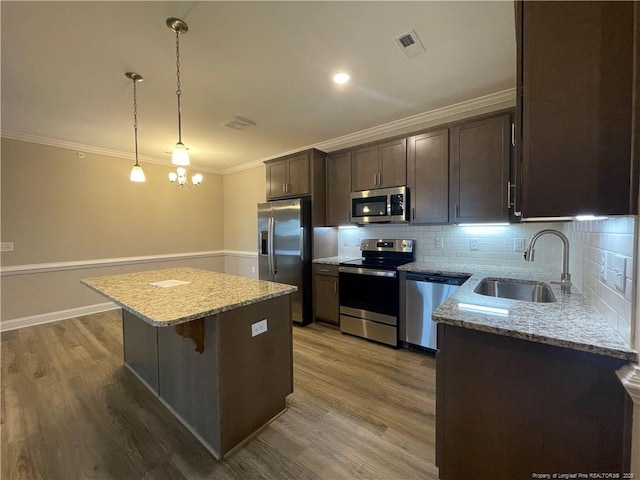 240 Gallery Dr Unit 301, Spring Lake, NC 28390 - kitchen featuring appliances with stainless steel finishes, a sink, a kitchen island, dark brown cabinets, and ornamental molding