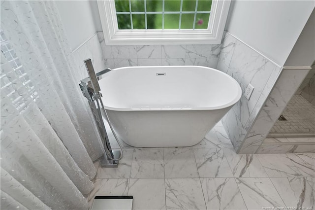 5387 Clubhouse Ln, Hope Mills, NC 28348 - bathroom featuring a soaking tub, wainscoting, marble look tiles, tile walls, and a shower with curtain