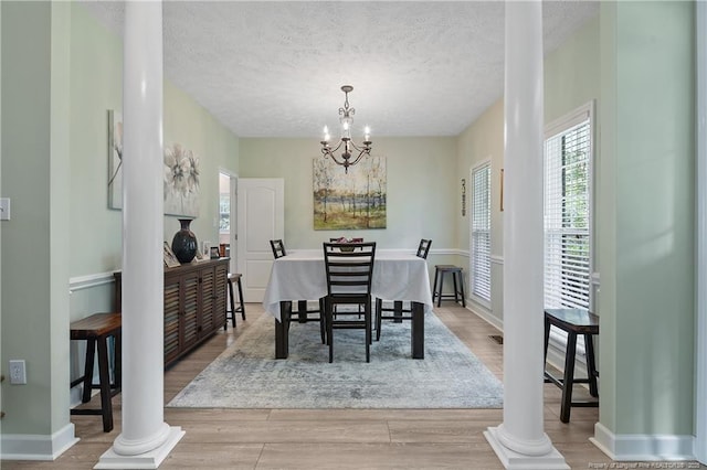 5387 Clubhouse Ln, Hope Mills, NC 28348 - dining area with light wood-style flooring, a textured ceiling, a chandelier, and ornate columns
