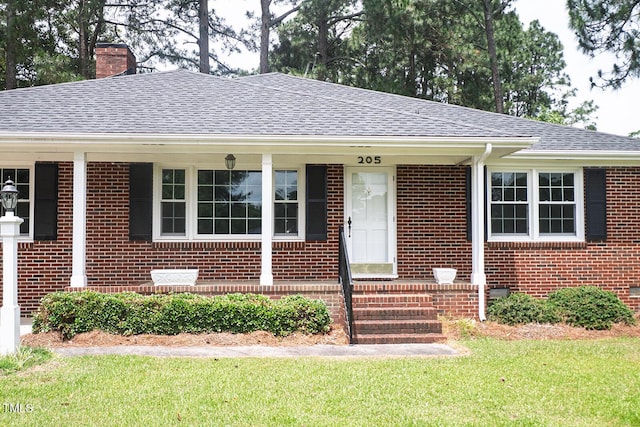 205 N Augusta Ave, Benson, NC 27504 - view of front of home with brick siding, a chimney, roof with shingles, a front yard, and a porch