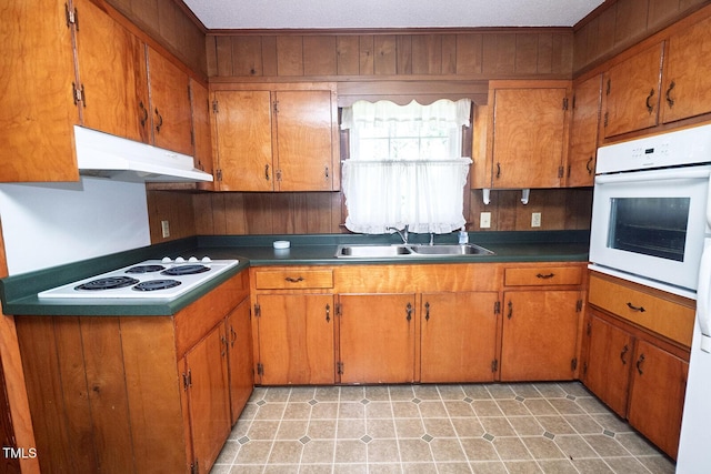 205 N Augusta Ave, Benson, NC 27504 - kitchen featuring white appliances, under cabinet range hood, a sink, brown cabinets, and wood walls