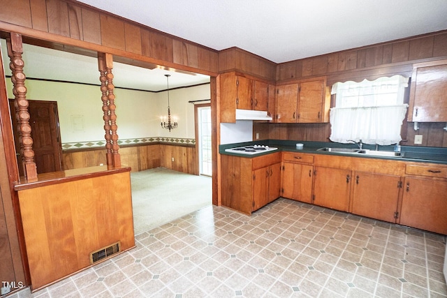 205 N Augusta Ave, Benson, NC 27504 - kitchen with a sink, under cabinet range hood, wooden walls, brown cabinets, and white stovetop