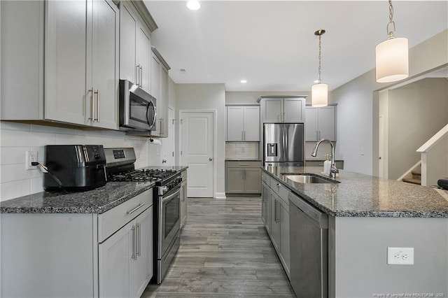 1664 Seattle Slew Ln, Hope Mills, NC 28348 - kitchen featuring stainless steel appliances, a sink, gray cabinetry, decorative backsplash, and wood finished floors