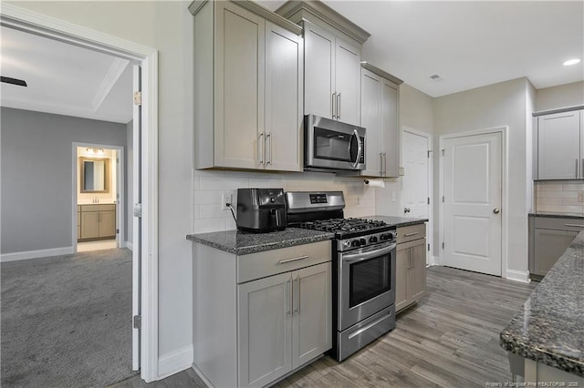1664 Seattle Slew Ln, Hope Mills, NC 28348 - kitchen with stainless steel appliances, gray cabinets, baseboards, backsplash, and dark stone countertops