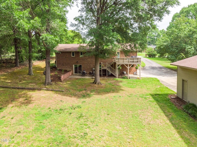 1822 Routh Rd, Burlington, NC 27217 - back of house featuring a deck, stairs, brick siding, driveway, and a yard