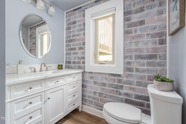 1822 Routh Rd, Burlington, NC 27217 - bathroom featuring vanity, toilet, brick wall, and wood finished floors