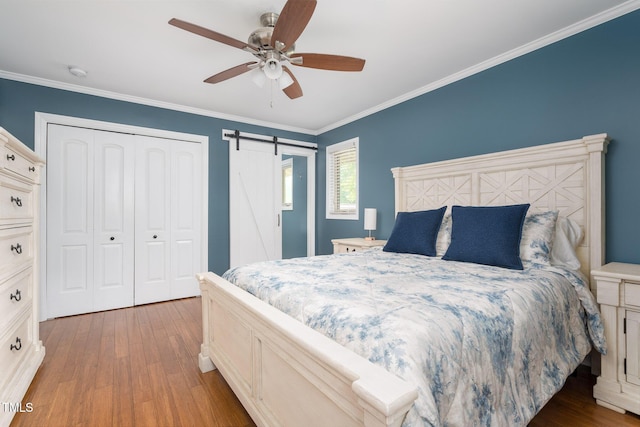 1822 Routh Rd, Burlington, NC 27217 - bedroom with wood-type flooring, ornamental molding, a barn door, a closet, and a ceiling fan