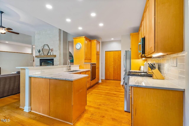 8821 Oconee Ct, Chapel Hill, NC 27516 - kitchen with open floor plan, stainless steel appliances, a sink, a peninsula, and light wood-style flooring