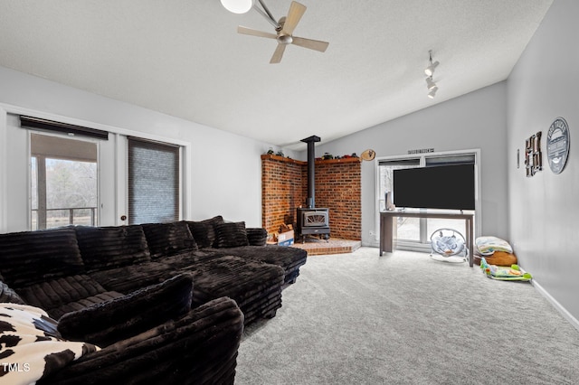 501 Enon Rd, Oxford, NC 27565 - carpeted living area with lofted ceiling, a wood stove, a ceiling fan, a textured ceiling, and baseboards