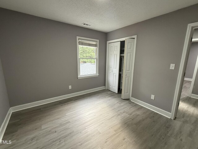 3825 Old Coach Rd, Raleigh, NC 27616 - unfurnished bedroom featuring wood finished floors, baseboards, a textured ceiling, and a closet