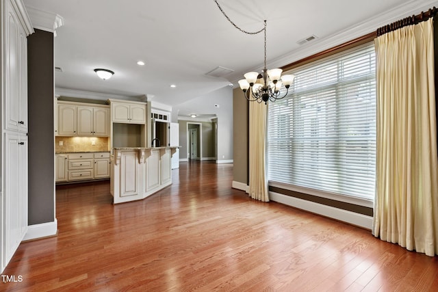3628 Eagle Farm Dr N, Wilson, NC 27896 - kitchen with a chandelier, a breakfast bar, crown molding, cream cabinets, and tasteful backsplash