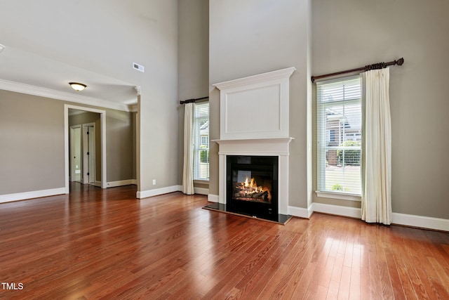 3628 Eagle Farm Dr N, Wilson, NC 27896 - unfurnished living room with wood finished floors, a glass covered fireplace, healthy amount of natural light, baseboards, and a high ceiling