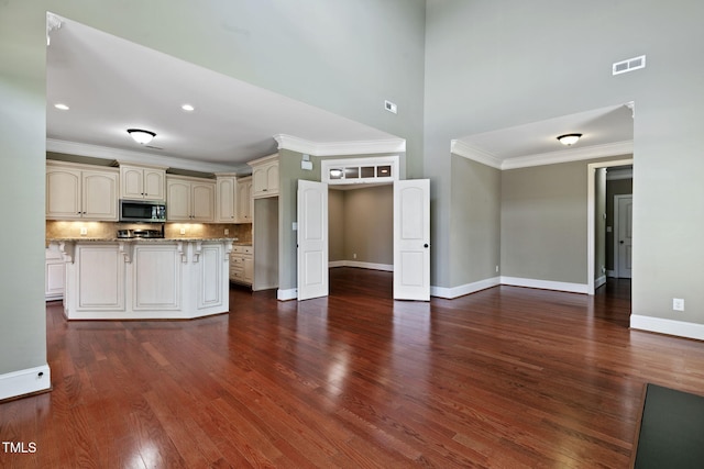 3628 Eagle Farm Dr N, Wilson, NC 27896 - kitchen with stainless steel microwave, cream cabinets, crown molding, dark wood-type flooring, and baseboards