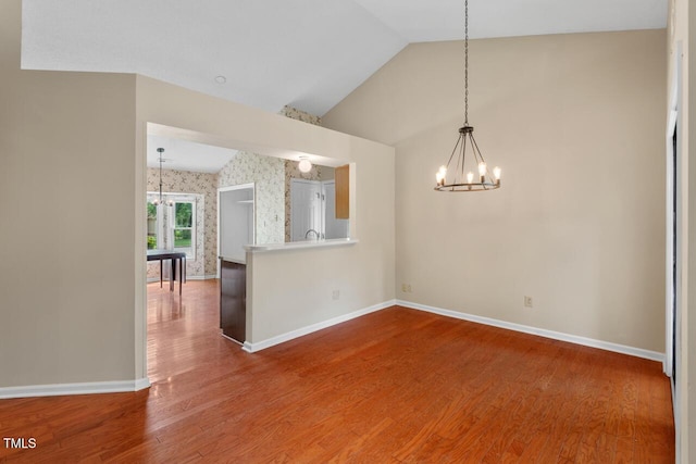 1014 Laurens Way, Knightdale, NC 27545 - unfurnished dining area featuring a chandelier, vaulted ceiling, baseboards, wood finished floors, and wallpapered walls