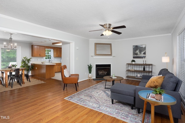 657 Lakeview Dr, Stem, NC 27581 - living area featuring light wood-style floors, a fireplace with raised hearth, a ceiling fan, a chandelier, and a textured ceiling