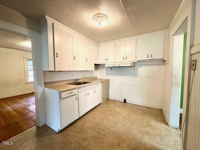 3810 Pendergrass St, Durham, NC 27704 - kitchen with a sink, white cabinets, light countertops, baseboards, and a textured ceiling
