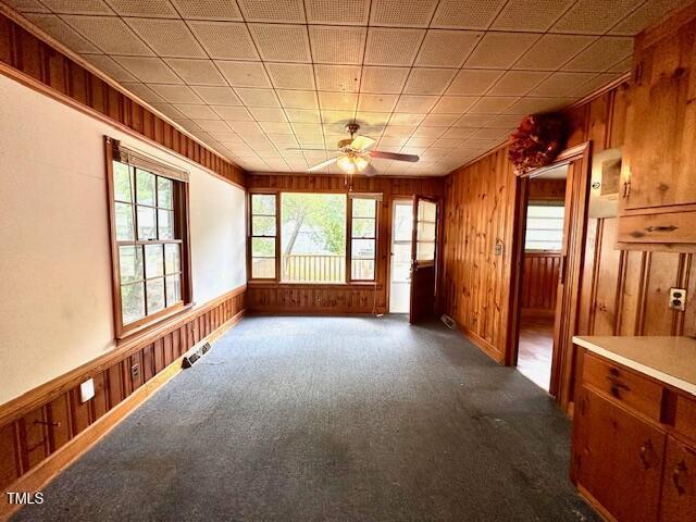 3810 Pendergrass St, Durham, NC 27704 - empty room with wooden walls, ceiling fan, and dark colored carpet