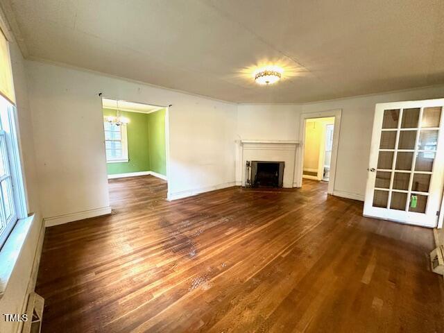3810 Pendergrass St, Durham, NC 27704 - unfurnished living room with wood finished floors, a chandelier, a fireplace, ornamental molding, and baseboards