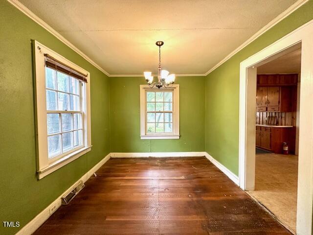 3810 Pendergrass St, Durham, NC 27704 - unfurnished dining area with healthy amount of natural light, a chandelier, crown molding, wood finished floors, and baseboards