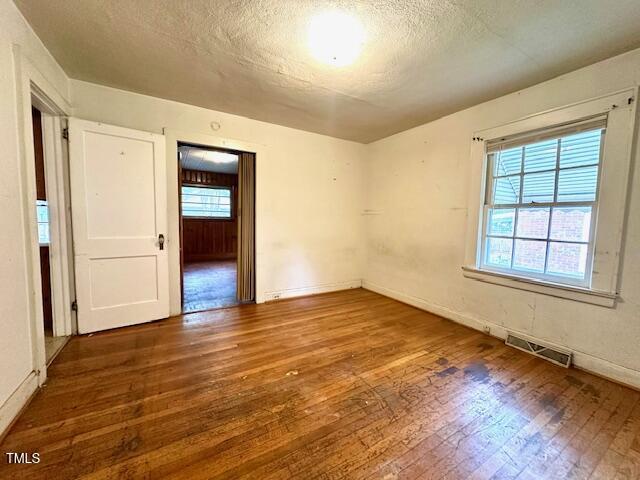 3810 Pendergrass St, Durham, NC 27704 - empty room featuring hardwood / wood-style floors, a textured ceiling, and baseboards