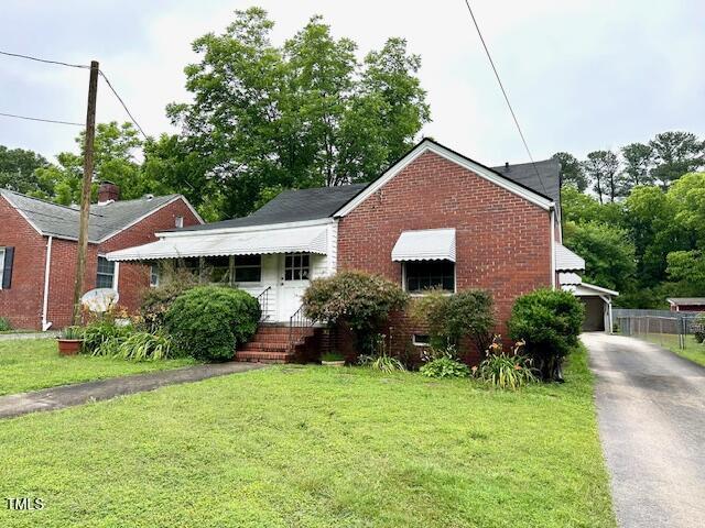 3810 Pendergrass St, Durham, NC 27704 - bungalow featuring brick siding, a front lawn, an outdoor structure, and asphalt driveway