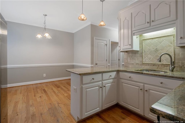 45 Remington Hills Dr, Bunnlevel, NC 28323 - kitchen featuring a peninsula, backsplash, a sink, pendant lighting, and white cabinetry