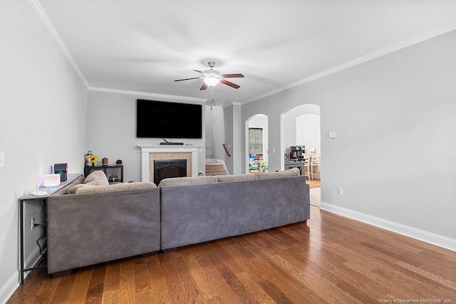 265 Tactical Dr, Bunnlevel, NC 28323 - living room featuring a fireplace, ornamental molding, a ceiling fan, arched walkways, and wood finished floors