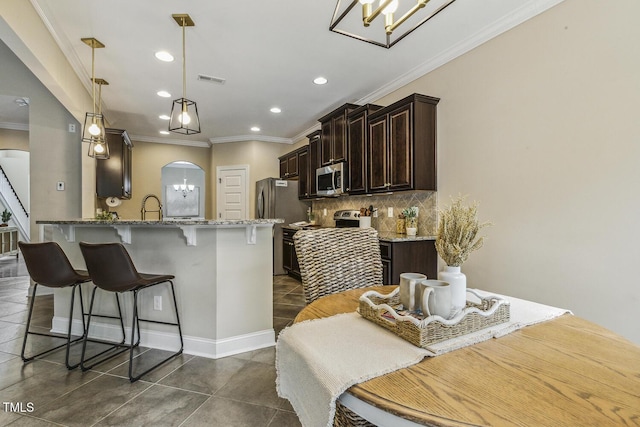 347 Country Mill Way, Fuquay Varina, NC 27526 - kitchen with stainless steel microwave, arched walkways, a breakfast bar area, dark brown cabinets, and ornamental molding